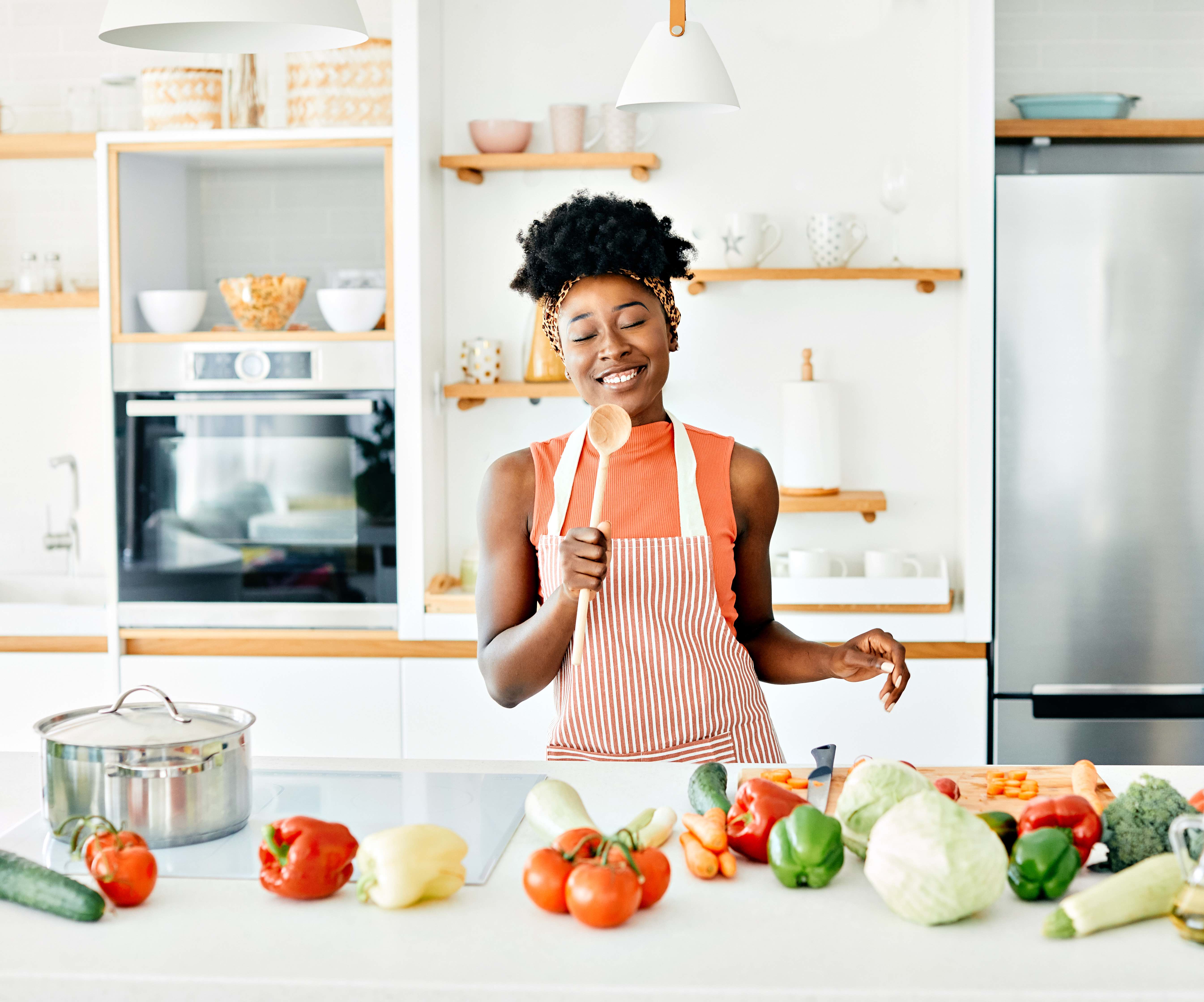 Happy woman cooking with fresh vegetables in a bright kitchen